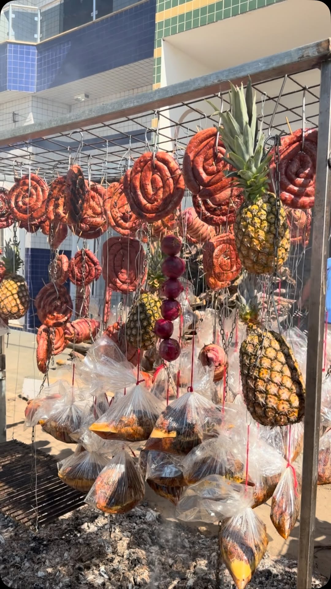 Mesa farta com espetos de carne, linguiça e abacaxi servidos em aniversário.
